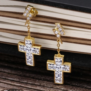Makroaufnahme von goldfarbenen Hip-Hop-Ohrringen mit glitzerndem Blitz- und Kreuz-Design