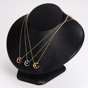 Quilted C-pendant stainless steel necklace in gold, silver and rose gold on display