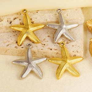 Detail view of gold and silver starfish pendants with textured surface on a stone base