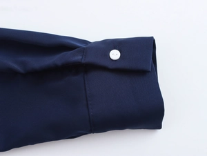 Detail of elegant navy satin dress cuff with white button and smooth silky texture