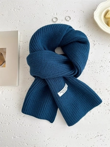 Dettaglio ravvicinato di sciarpa in lana blu navy con trama a maglia spessa e etichetta
