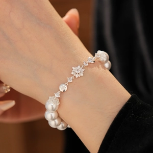 Gros plan d'un bracelet de perles avec des breloques fleurs en zircone et perles blanches