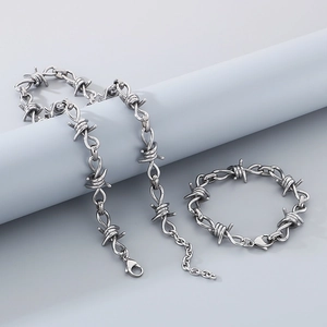 Detailed view of silver thorn wire punk necklace and bracelet set on display pedestals