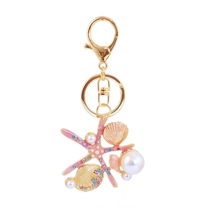 Macro detail of starfish keychain with golden shells, colorful crystals and white pearls