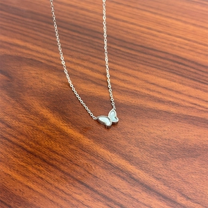 Detailed close-up of butterfly pendant necklace with white shell inlay and beaded edges
