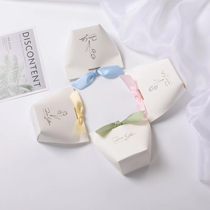 Close-up of pastel wedding favor boxes with satin ribbons and floral for you printing