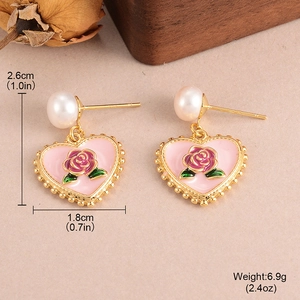 Vintage heart rose pearl earrings with gold frame on beige textured background