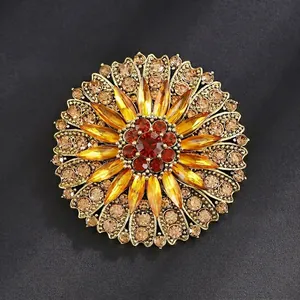 Vintage gold sunflower brooch with amber crystal petals on a dark textured surface