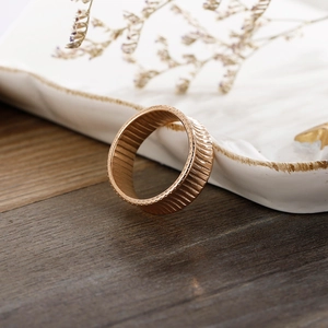 Detail of 18K gold plated striped ring showing unique texture on a wooden surface