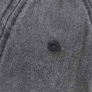 Detailed macro view of dark grey washed cotton fabric with stitching and eyelet on a cap