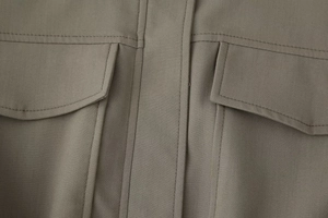 Detail of khaki cotton jacket showing symmetrical chest flap pockets and fine stitching