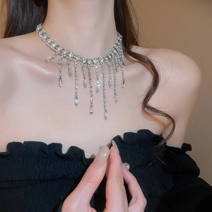 Macro view of silver tassel necklace with rhinestones and teardrop pendants on a model