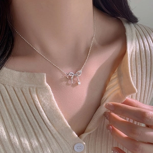 Close-up of a silver bow necklace with sparkling crystals on a female model's neck