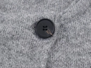 Close-up of grey knit fabric texture with a detailed black four-hole resin button