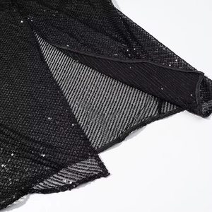 Detail of black sequined evening dress featuring mesh fabric and a stylish side slit