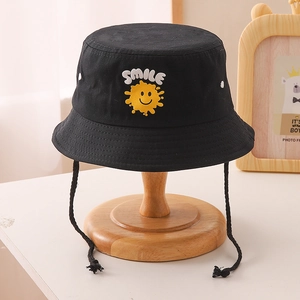 Détail de la broderie soleil jaune et texte blanc sur le chapeau bob noir pour enfants