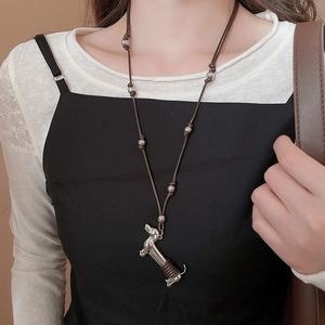 Detail of silver dachshund puppy pendant necklace on brown cord worn by a model