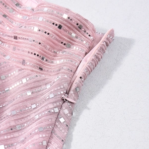 Détail du tissu à paillettes roses avec fermeture éclair invisible et broderie brillante