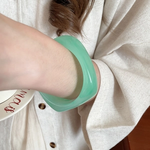 Detail view of a light green resin geometric bracelet on a wrist with vintage retro style
