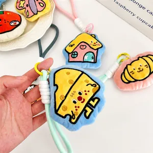 Detalle de un llavero de peluche de dibujos con bordado y asa de cuerda tejida