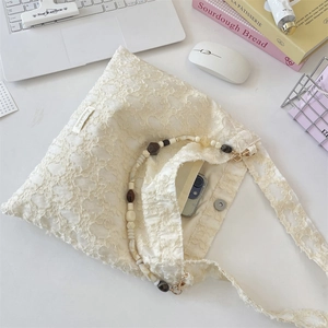 Detailed macro view of white floral lace handbag with colorful beaded strap and magnetic closure