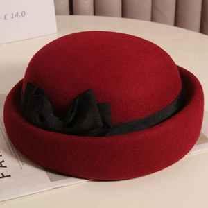 Dettaglio del cappello bowler in lana bordeaux con fiocco nero e tesa arricciata