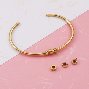 Adjustable gold stainless steel bangle with spherical spacer beads on dual-tone background