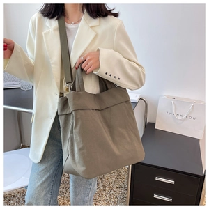 Detail of army green nylon tote bag worn over the shoulder with a stylish white blazer