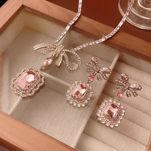 Silver necklace and earrings set with pink crystals and zircon bow design