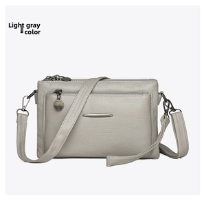 Detail shot of light gray PU leather crossbody bag featuring multi-layer zipper pockets