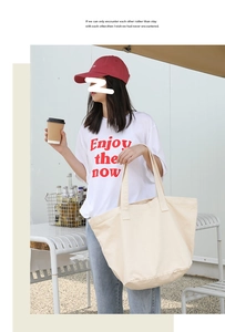 Close-up of a large off-white canvas tote bag in a casual outdoor cafe setting