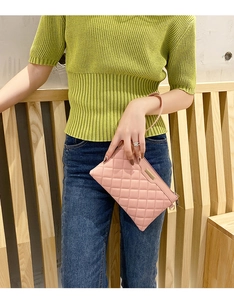 Detail of pink quilted PU leather clutch bag with metal zipper and wrist strap on model