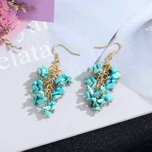 Detail of bohemian turquoise stone tassel earrings with elegant gold multi-layered chains