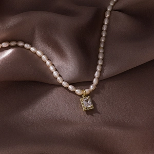 Détail de l'image de perles de riz blanches et pendentif zircon doré sur soie marron
