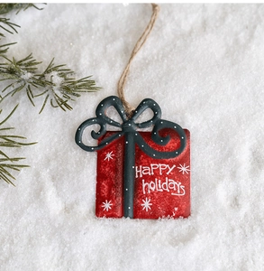 Detail of red metal gift box ornament with Happy Holidays text on snowy background