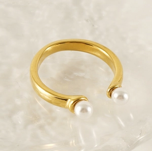 Détail d'une bague ouverte en acier inoxydable doré 18 carats avec deux perles blanches