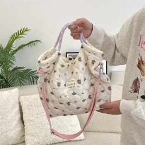 Détail du sac matelassé en toile crème avec motif de chien et bandoulière rose
