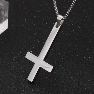 Close-up of polished silver titanium steel inverted cross pendant on a black textured background