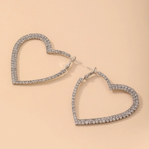 Detailed view of oversized silver heart hoop earrings with sparkling rhinestones