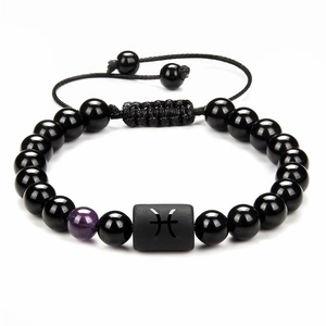 Detail of obsidian zodiac bracelet with Pisces symbol and adjustable woven cord