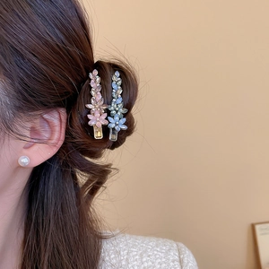 Détail de pinces à cheveux fleur en cristal rose et bleu portées sur un chignon