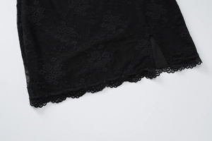 Detailed close-up of black lace dress showing intricate floral patterns and split hem edge
