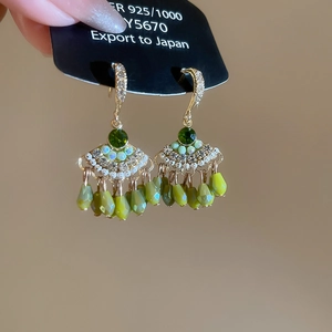 Dettaglio orecchini a ventaglio in argento 925 con cristallo verde e frange di nappe