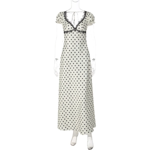 Dettaglio dello scollo a V con pizzo nero su un abito beige a pois da donna