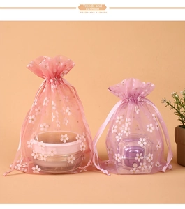 Detailed view of pink organza drawstring bags with white floral prints and ribbon closure