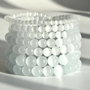Stacked white opal stone beaded bracelets in multiple sizes with cat-eye effect shimmer