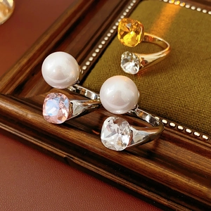 Close-up of gold and silver open rings with white pearls and square-cut glass crystals