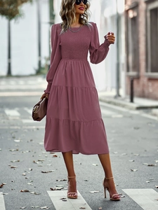 Détail du bustier plissé fuchsia et des manches lanternes sur une robe mi-longue