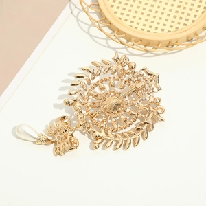 Detail of gold brooch back showing secure pin clasp, intricate leaf design and pearl drop