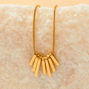 Gold bohemian tassel necklace with rectangular fringe on a crystal stone background